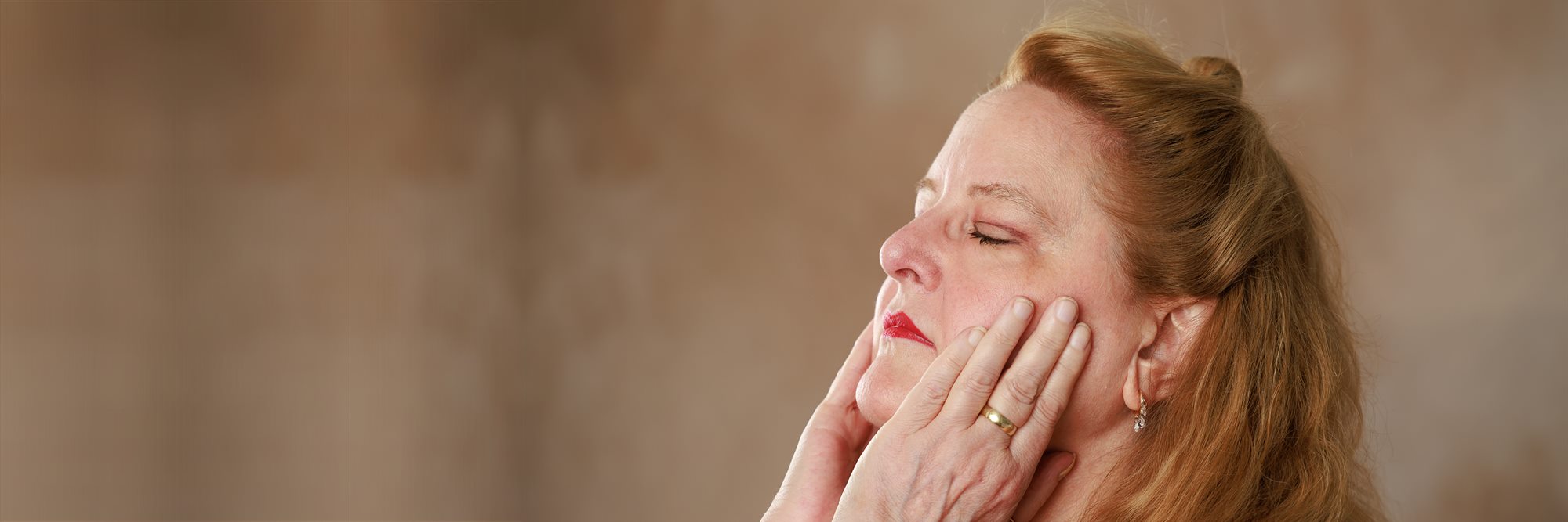 Sally Seaver with her eyes closed, both hands resting against her face.