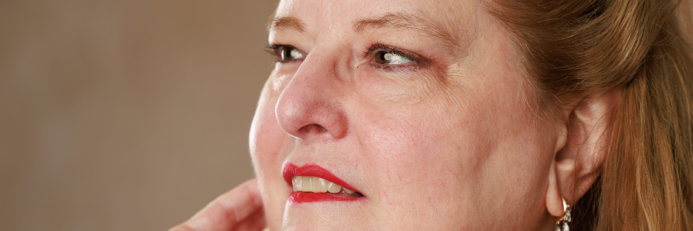 Sally Seaver in close profile, one hand raised near her jaw, looking to one side in soft studio light.