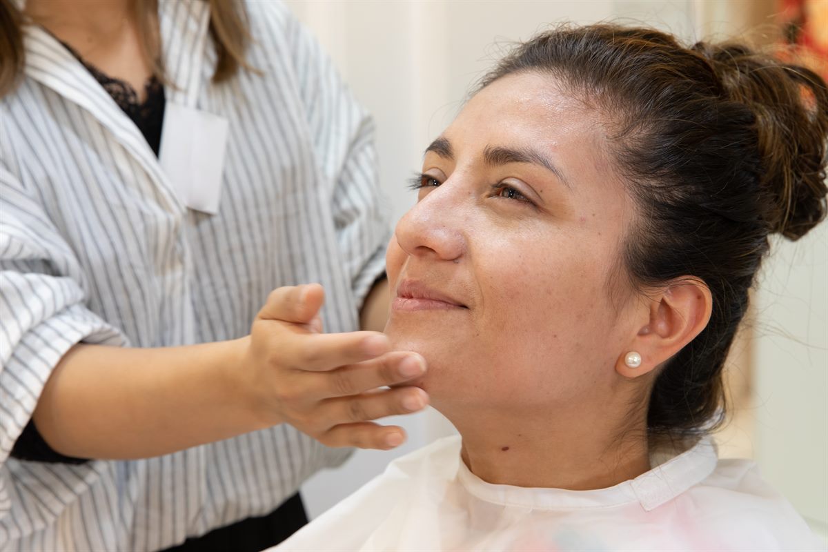 A woman having her face examined, another person's hand resting lightly beneath her chin.
